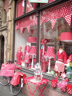 red and white polka dot decorations on display in the window of a storefront with bicycles parked outside