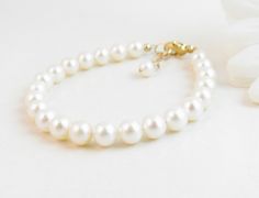 "A classic real freshwater pearl bracelet for newborn, infant, baby, child, little girl, tween or teen. This keepsake bracelet is created with Grade-A 5.5mm round freshwater pearls and a 14K gold-filled oval lobster clasp with a 1/2\" \"Grow with Me\" extender chain. Arrives packaged in my signature high-quality reusable canvas gift bag. Beautiful and ready for gift giving. S I Z I N G . G U I D E The bracelet should be 3/4\" larger than her snug wrist measurement. If you are unable to measure, Classic Adjustable Hypoallergenic Pearl Bracelet, Elegant Pearl Jewelry For Baptism, Elegant Adjustable Pearl Bracelet For Baptism, Elegant Pearl Rosary Bracelet For Baptism, Classic Adjustable Jewelry For First Communion, Elegant Pearl White Jewelry For Baptism, Elegant Pearl Bracelet For First Communion, Elegant Pearl Bracelet With Pearl Charm For First Communion, White Hypoallergenic Pearl Bracelet For First Communion