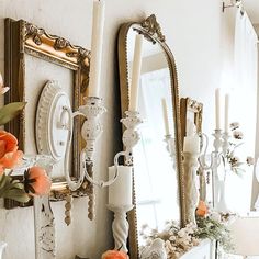 there are many mirrors on the wall with flowers in vases and candlesticks