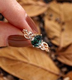 a woman's hand holding a green ring with leaves around it and the top part of her finger