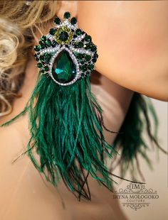 a close up of a woman's ear with green feathers and jewels on it