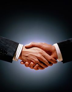 two people shaking hands with one holding the other's hand, against a dark background