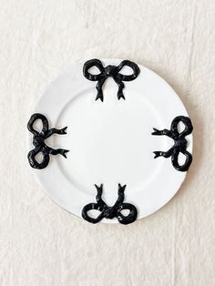 a white plate topped with black bows on top of a table next to a wall