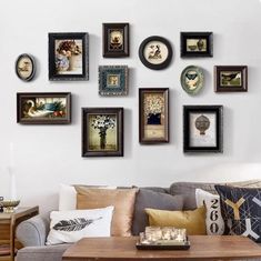 a living room filled with lots of framed pictures on the wall next to a couch