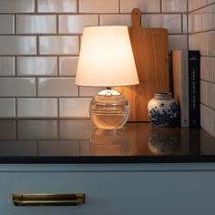 a lamp is sitting on top of a table next to books and a book case