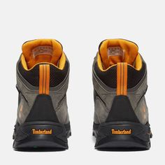 the back view of a pair of hiking shoes with orange and black accents on them