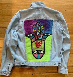 a denim jacket with an image of a hand painted on it