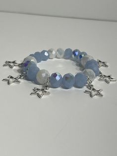 This Bracelet features beautiful blue and white beads that shine like stars when they catch the light and silver star charms to add that celestial feel of having the sky dance on your wrist.  Perfect for a Celestial Goddess wanting a touch of magic or to complete that pastel outfit with this versatile bracelet! Created with durable beads and heavy duty elastic string.  Made in 7.5 inches but can be customized to fit in either 7 inches or 8 inches. 7 inches is recommended for very small wrist whi Blue Handmade Star-shaped Beaded Bracelets, Silver Beaded Bracelets With Star Charm, Silver Beaded Bracelet With Star Charm And Round Beads, Blue Beaded Star-shaped Bracelets, Blue Beaded Bracelets With Star Charm For Gift, Blue Bracelets With Star Charm And Round Beads, Blue Beaded Bracelets With Star Charm, Celestial Bracelet, Celestial Goddess