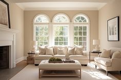 a living room filled with furniture and a fire place in front of two large windows