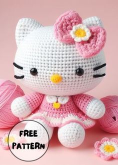 a crocheted hello kitty doll sitting next to pink yarn