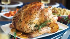 a roasted turkey with potatoes and herbs on a white plate