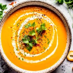 a bowl filled with carrot soup and garnished with parsley