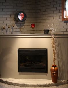 a fire place in a living room next to a wall with a clock on it