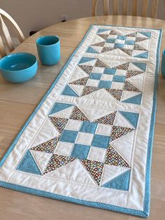 a table runner with blue bowls and cups on it, along with a wooden dining room table