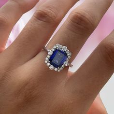 a woman's hand with a diamond and blue stone ring on top of it