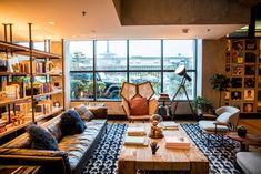 a living room filled with furniture and bookshelves next to a large glass window