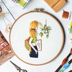 a woman is sitting in front of a cross - stitch pattern with scissors and thread