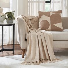 a living room with a couch, table and chair covered in a beige throw blanket