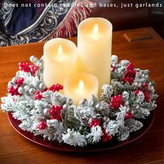 three lit candles sitting on top of a red plate covered in holly wreaths and berries