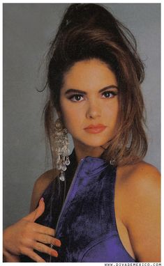 a young woman in a purple dress posing for the camera with her hand on her hip