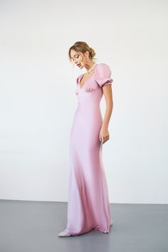 a woman in a pink dress posing for the camera with her hand on her hip