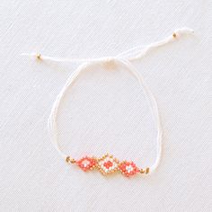 UPAVIM Crafts is excited to announce its brand new seed bead jewelry line with each piece in the collection named after one of the talented artisans who made them! Our Naomi Seed Bead Bracelet features stunning coral, white, and gold beads threaded in an incredibly delicate and intricate pattern. Lightweight and comfortable to wear - truly remarkable! As always, Handmade and Fair Trade! 100% Cotton Thread Czech Glass Seed Beads Adjustable: 4'' - 14'' Circumference Did you know that our unique se White Friendship Bracelets With Gold Beads As A Gift, White Friendship Bracelets With Faceted Round Beads, White Dainty Bracelet With Faceted Beads, White Friendship Bracelet With Gold Beads As Gift, White Jewelry With Faceted Beads For Festival, White Tiny Beads Friendship Bracelets For Jewelry Making, Adjustable Coral Beaded Bracelets As Gift, White Beaded Bracelets With Spacer Beads For Festivals, White Beaded Bracelets With Gold Beads As Gift