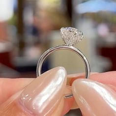 a person holding a diamond ring in their hand