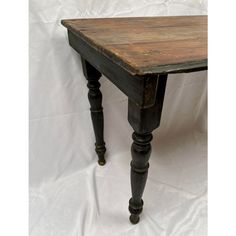 an old wooden table sitting on top of a white sheet