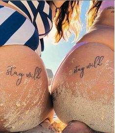 two women sitting on the beach with their butts covered in sand and writing that says stay wild