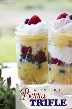 two mason jars filled with berry trifle desserts on top of a white table