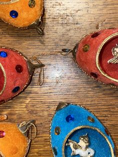 four different colored purses on a wooden table with metal handles and decorations around them