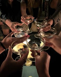 many people are holding wine glasses together