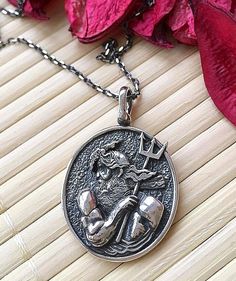 a close up of a necklace on a wooden surface with flowers in the back ground