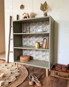 a green bookcase with books and shoes on the floor