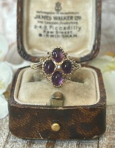 A beautifully elegant vintage amethyst and diamond cluster ring crafted in solid 9 carat yellow gold.  This lovely statement ring exudes a classic antique charm and is set with four oval deep purple cabochon cut amethyst gemstones arranged symmetrically to form an enchanting cluster.  At the heart of the ring lies a small round cut sparkly diamond which draws the eye with its subtle captivating shimmer.  The setting is ornate by design and features elegant scrolled shoulders adding a touch of so Diamond Rings Vintage, Amethyst Ring Vintage, Gold Schmuck, Gold Amethyst Ring, Gold Jewelry Gift, Vintage Gold Rings, Ring Crafts, February Birthstone, Lovely Ring