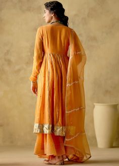 Features a tangerine front open silk anarkali embellished with zari & patra work, finished with gota lace & button detailing on the front. Completed with a matching sharara with lace detailing and an embellished dupatta. Composition : Anarkali & Sharara: Chanderi Silk Lined with Mul Cotton, Dupatta: Organza Care: Dry Clean Only and Vacuum Storage All products can be customised for sleeves, length of blouse and neck design Delivery : 3-4 weeks as the product is hand crafted. Check Size Guide or choose MySize for free customisation (All Sizes above XL can be made at 15% additional cost) For more information and sizes please contact fabiliciousfashion@gmail.com or visit our Copenhagen studio. Orange Anarkali, Silk Anarkali, Cotton Dupatta, Lace Button, Sharara Set, Lace Embroidery, Anarkali, Aza Fashion, Neck Designs