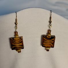 a pair of zebra print earrings on a mannequin's torso, with gold accents