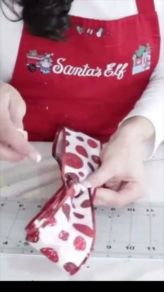 a woman in an apron is cutting fabric with scissors