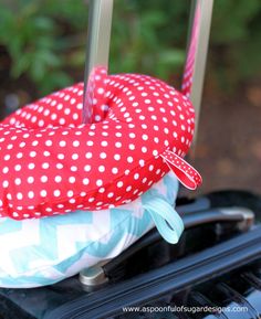 a red and white polka dot heart shaped pillow sitting on top of a piece of luggage