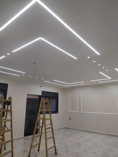 two ladders are in the middle of a room with white walls and ceiling lights