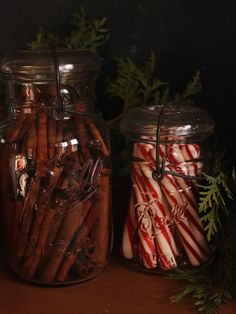 two glass jars filled with cinnamon sticks and candy canes