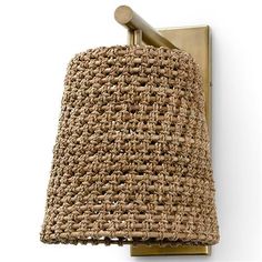 a light that is on the side of a wall with a woven lamp shade hanging from it