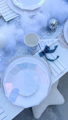 the table is set with white plates and silverware, blue napkins, and snowflakes