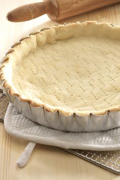 an uncooked pie sitting on top of a cooling rack next to a rolling pin