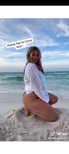 a woman sitting on top of a sandy beach next to the ocean with a message above her head