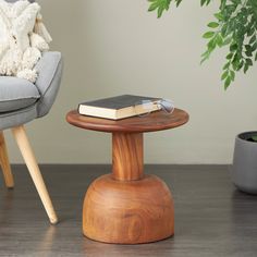 a wooden table with a book on it next to a chair and potted plant