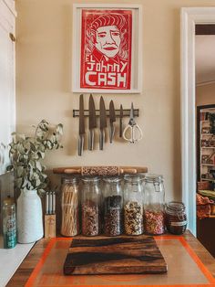 a kitchen counter with spices and utensils on it next to a framed poster