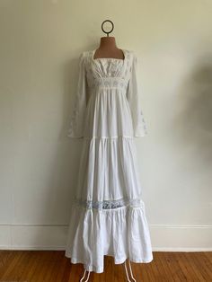 Beautiful gown, Gunne Sax label missing but I have seen this particular style more than twice.  Length: 55", Waist: 13.5" measured at rib from 14" drop from top hem Small stain at bust. Gimme Sax Wedding Dress, White 70s Dress, 1970s Prairie Dress, White Cotton Maxi Dress With Fitted Bodice, White Bohemian Maxi Dress With Square Neck, Cotton Maxi Dress With Fitted Bodice, Vintage Empire Waist Maxi Dress For Wedding, Vintage Empire Waist Wedding Maxi Dress, Fitted Bohemian Maxi Dress For Gatherings