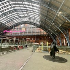 the inside of an indoor train station with people walking around and one person in a black coat