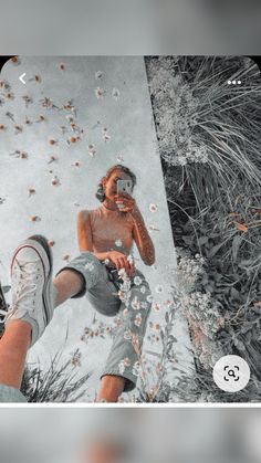 a man taking a selfie with his cell phone in front of flowers and grass